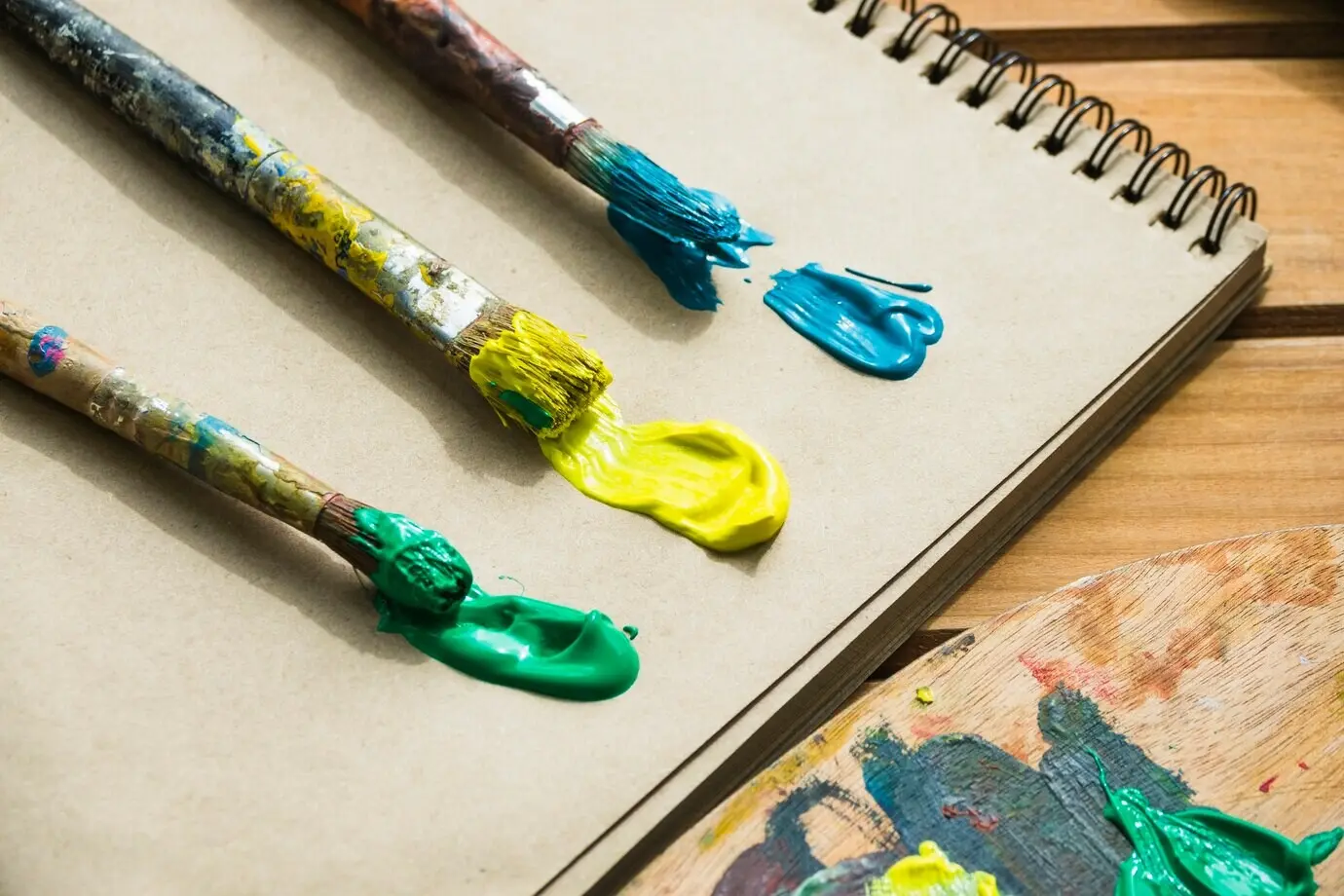 Pinseltrio mit Farbe auf einem Notizbuch.