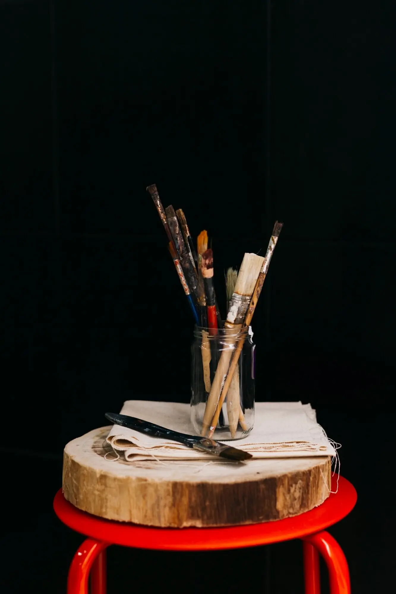 Auf einem Hocker steht ein Glas mit Pinseln.